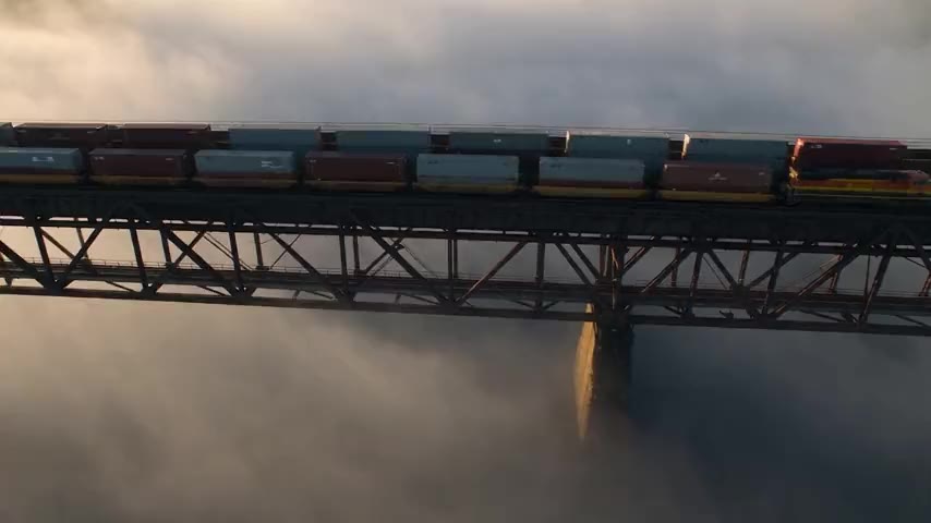 Güterzug mit Containern auf einer Stahlbrücke im Nebel